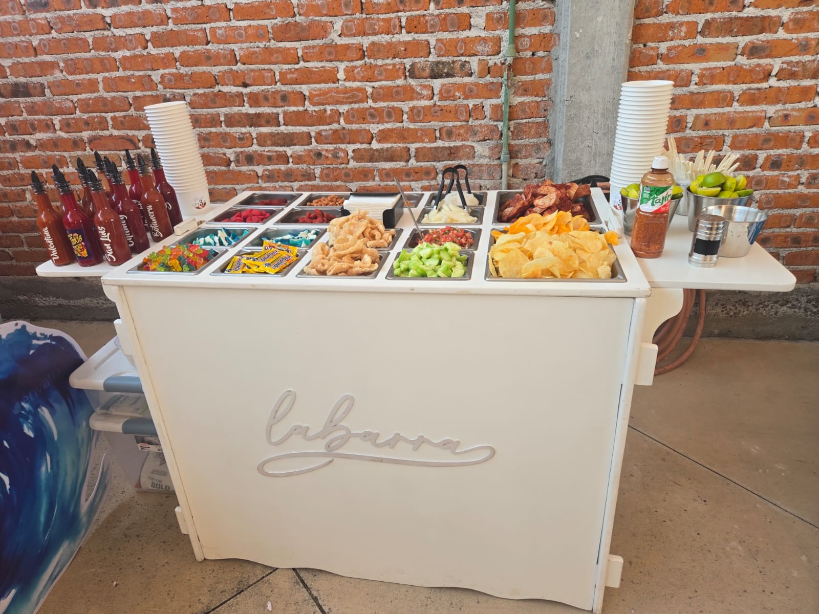 Barra de snacks montada en evento con pared de ladrillo